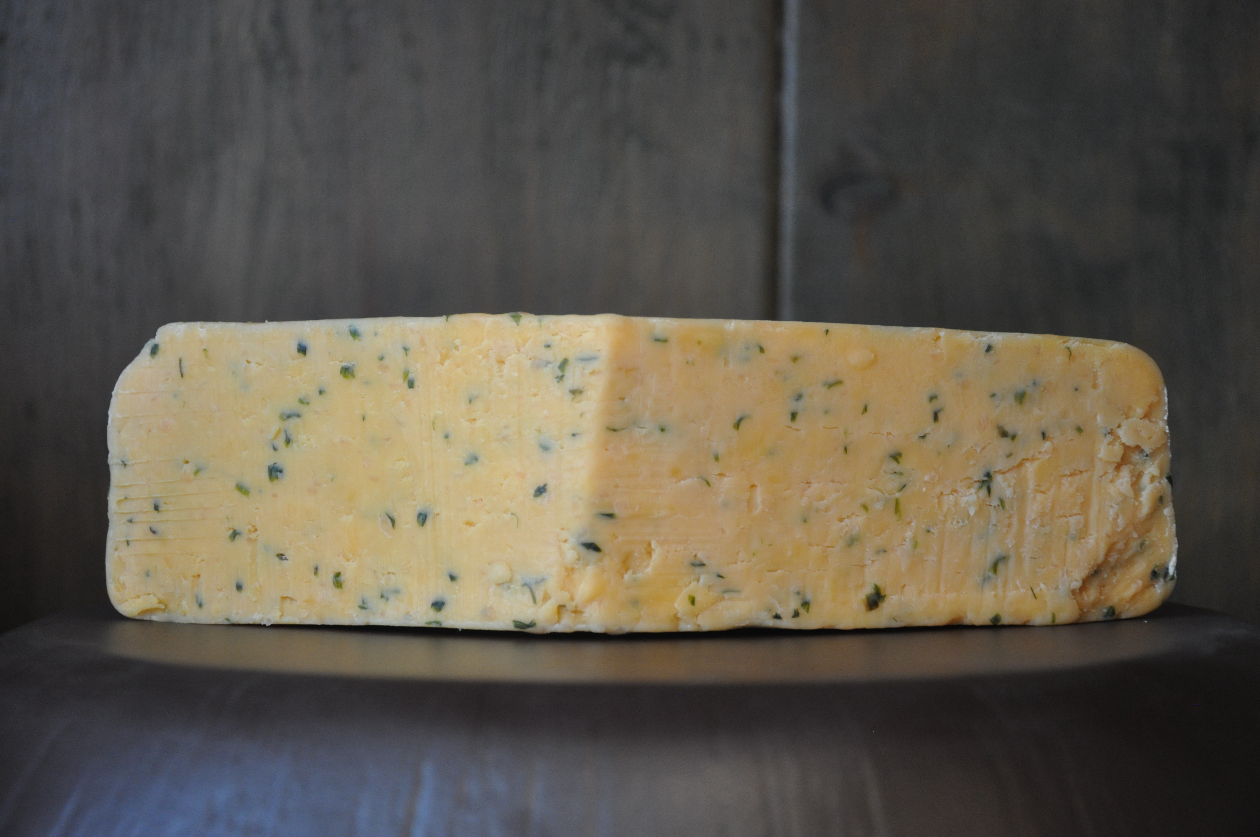 Block of Double Gloucester cheese with visible chive pieces